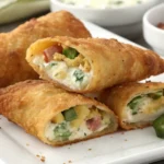 Golden-brown jalapeño popper egg rolls filled with creamy cheese, jalapeños, and shredded chicken.